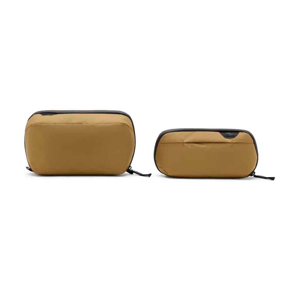 The Peak Design Wash Pouch in coyote tan, shown next to the smaller Small Wash Pouch version